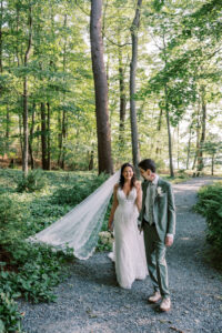 Bride and groom walk through the woods at Saphire Estate
