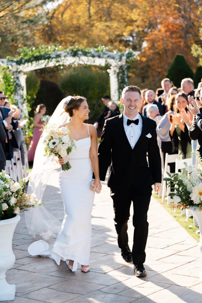 Bride and groom walk back down the aisle at the pergola