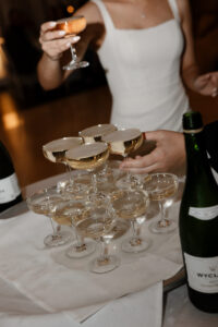 Bride and groom cheers champagne from champagne tower at wedding reception