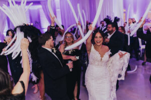 Bride and groom dance with guests at wedding on ballroom dance floor